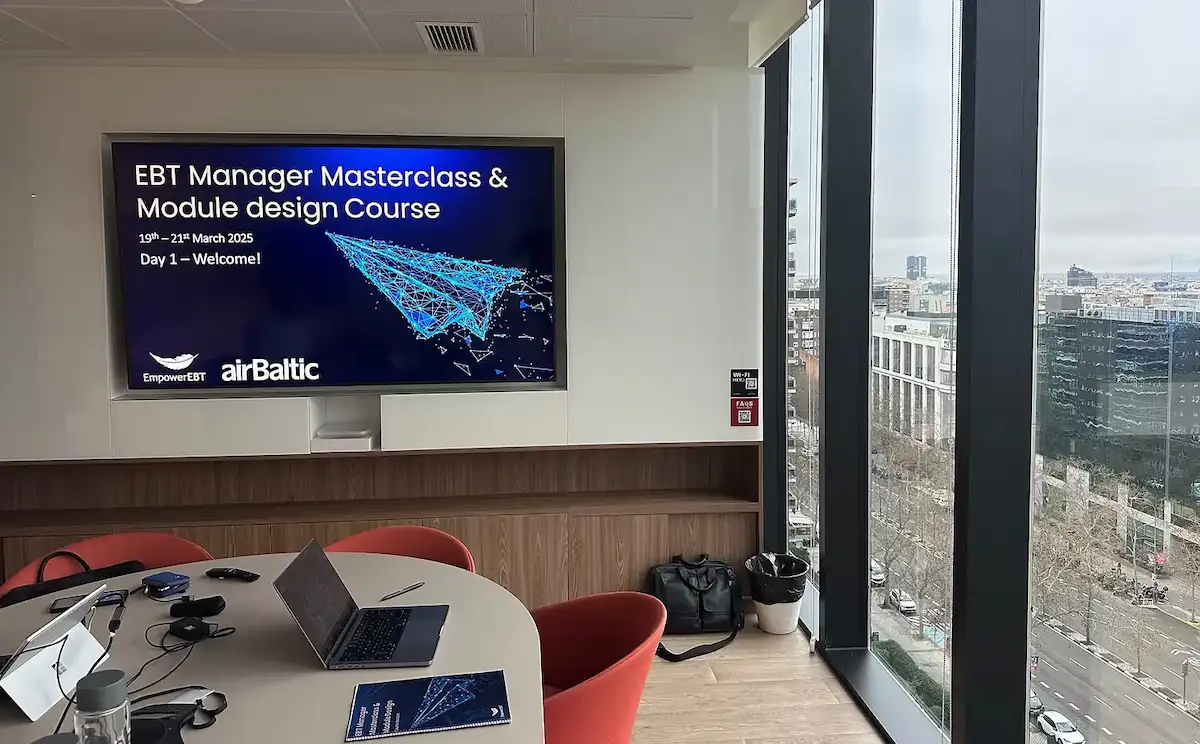 Classroom view of an Empower.aero Airbaltic EBT Manager Masterclass workshop on screen, with glass windows overlooking Madrid